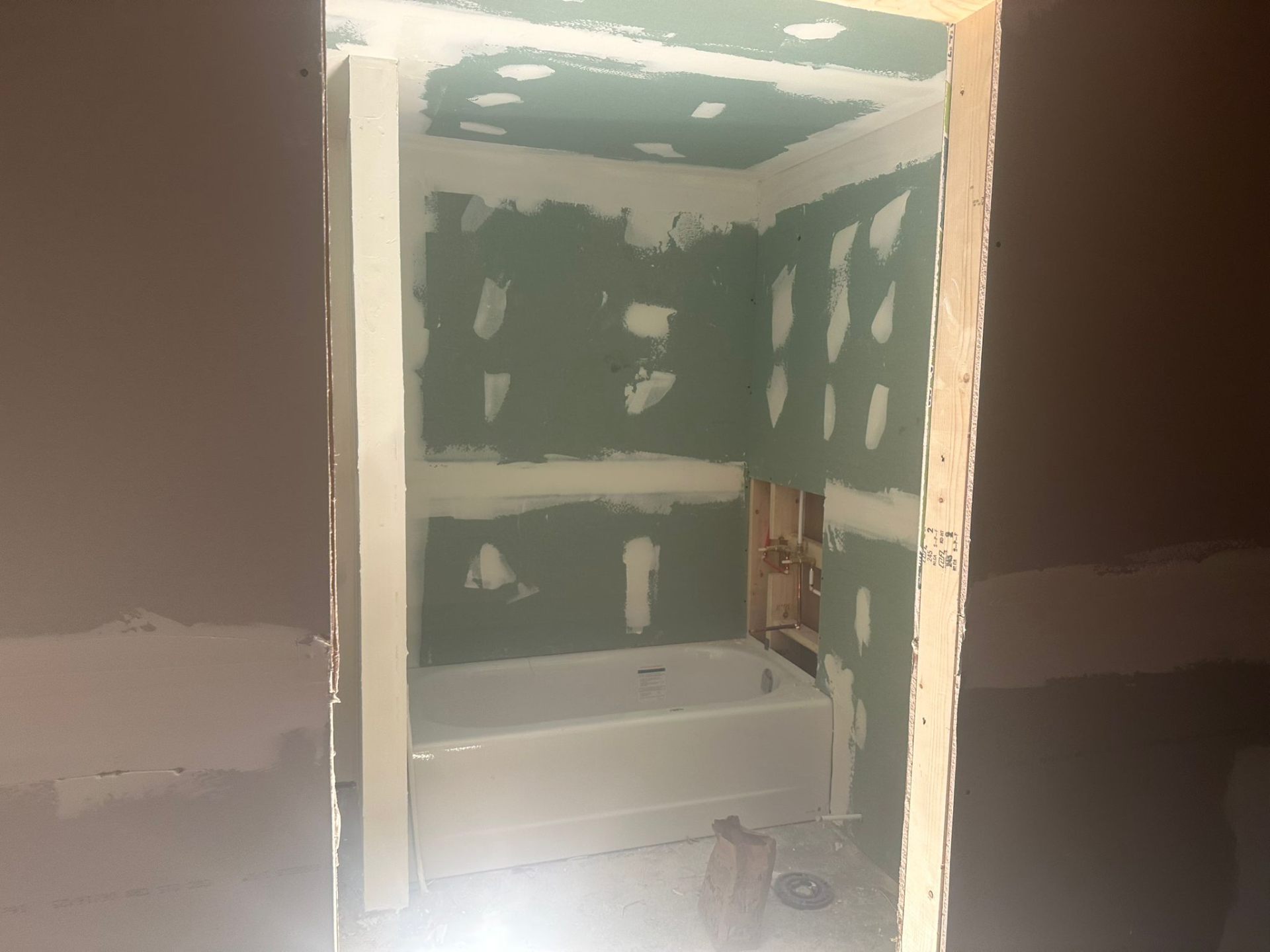 Basement bathroom rough-in with moisture-resistant green board installed around the tub, mudded and ready for tile
