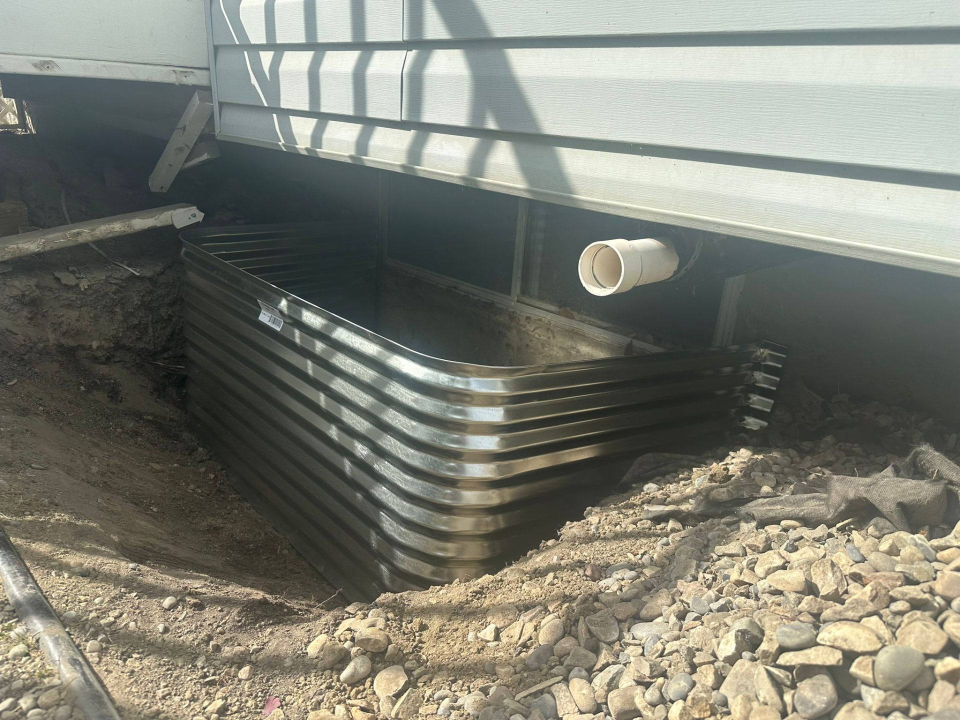 Galvanized corrugated metal egress window well installed against the foundation