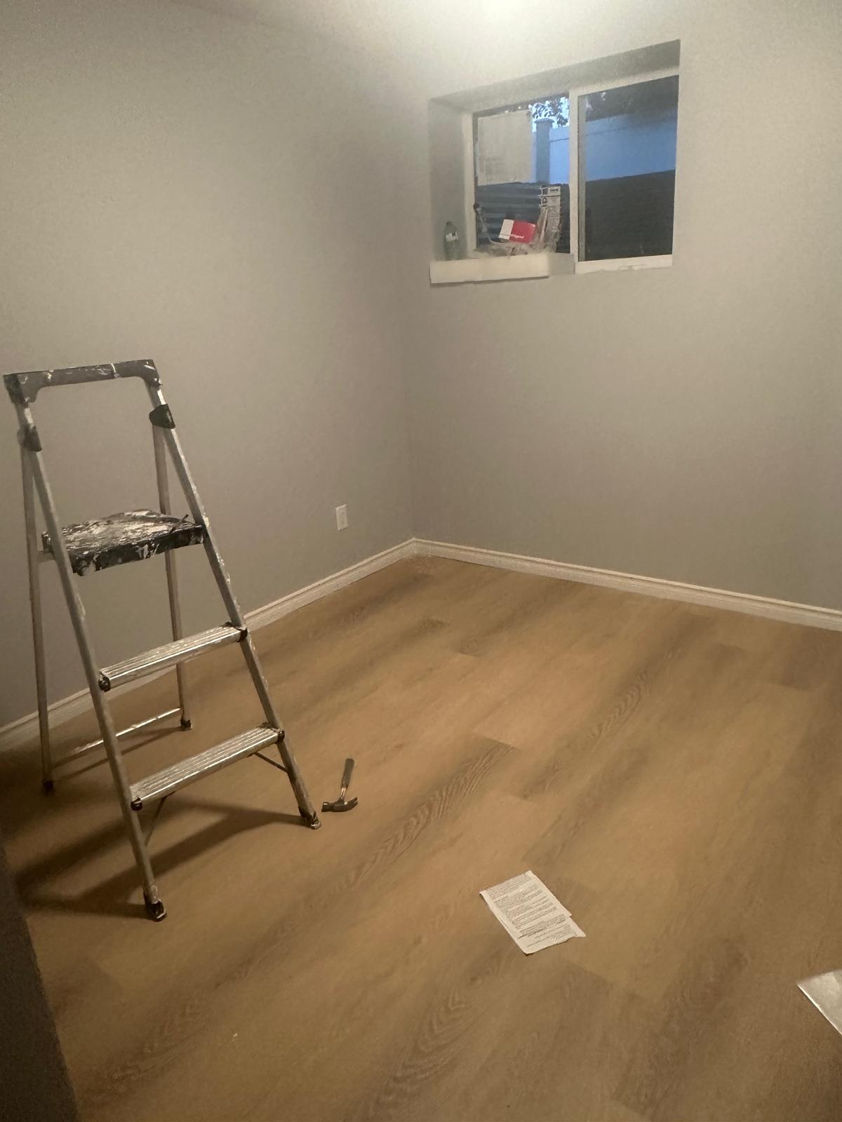 Finished basement bedroom interior with new egress window, painted walls, baseboards and luxury vinyl plank flooring