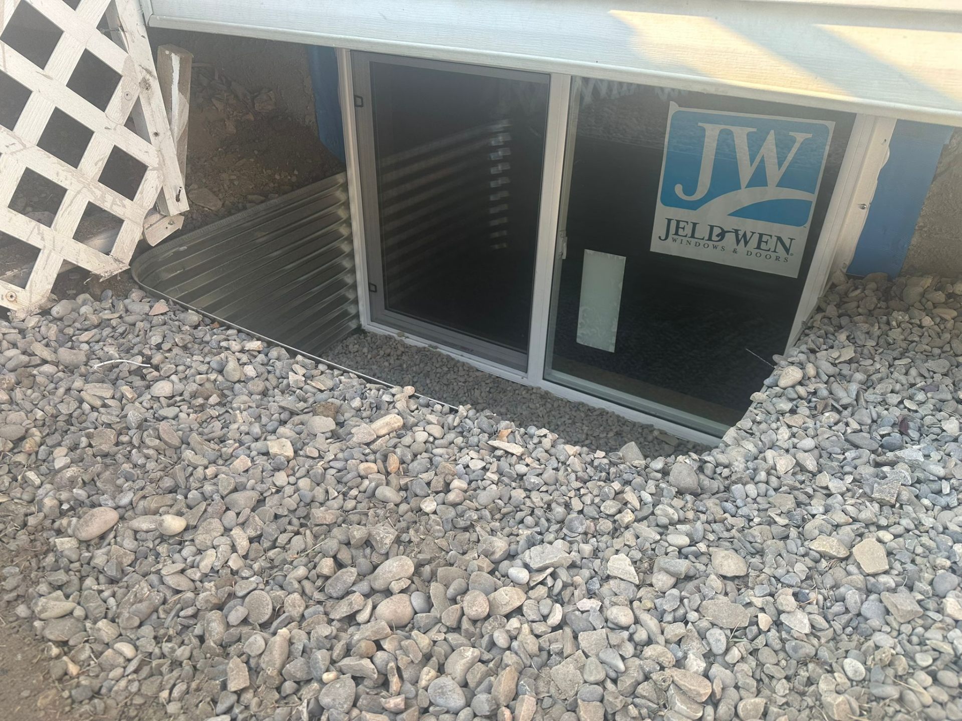 Finished basement egress window with rock-filled well and clean grading