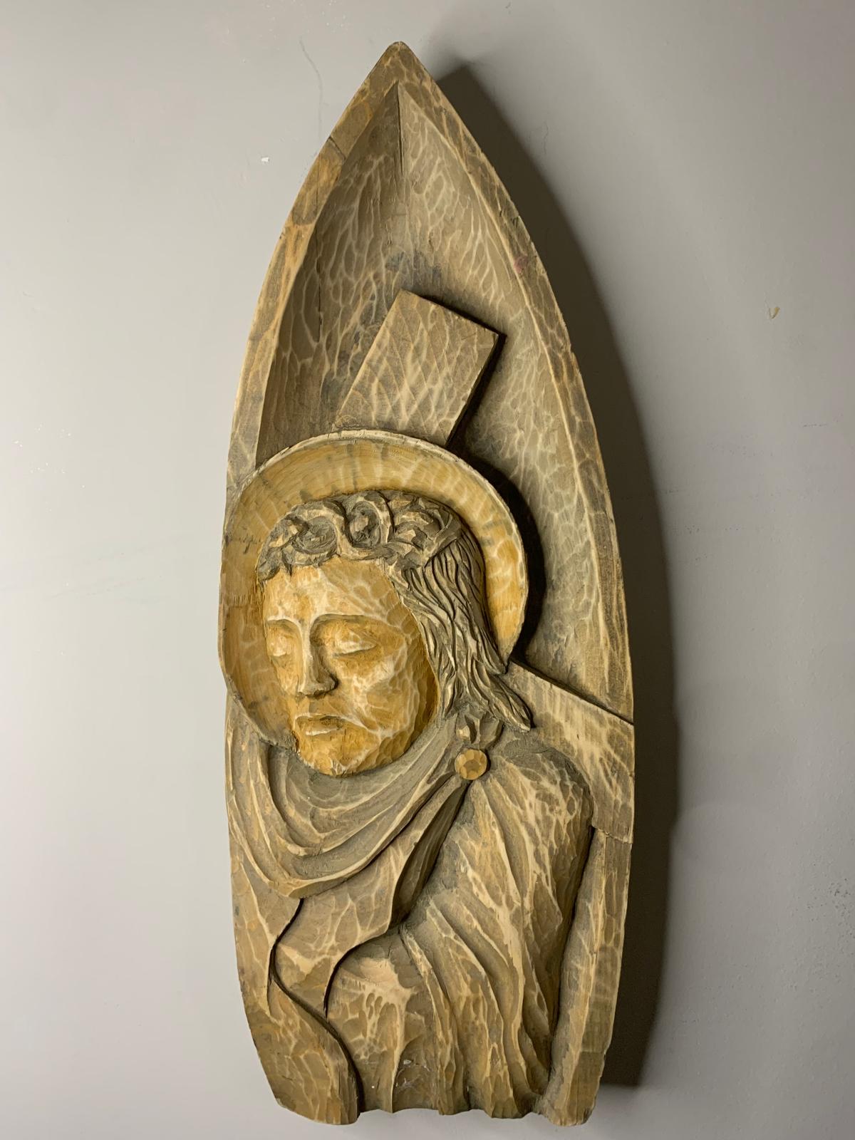 Tall arched wooden carving of a haloed saint figure