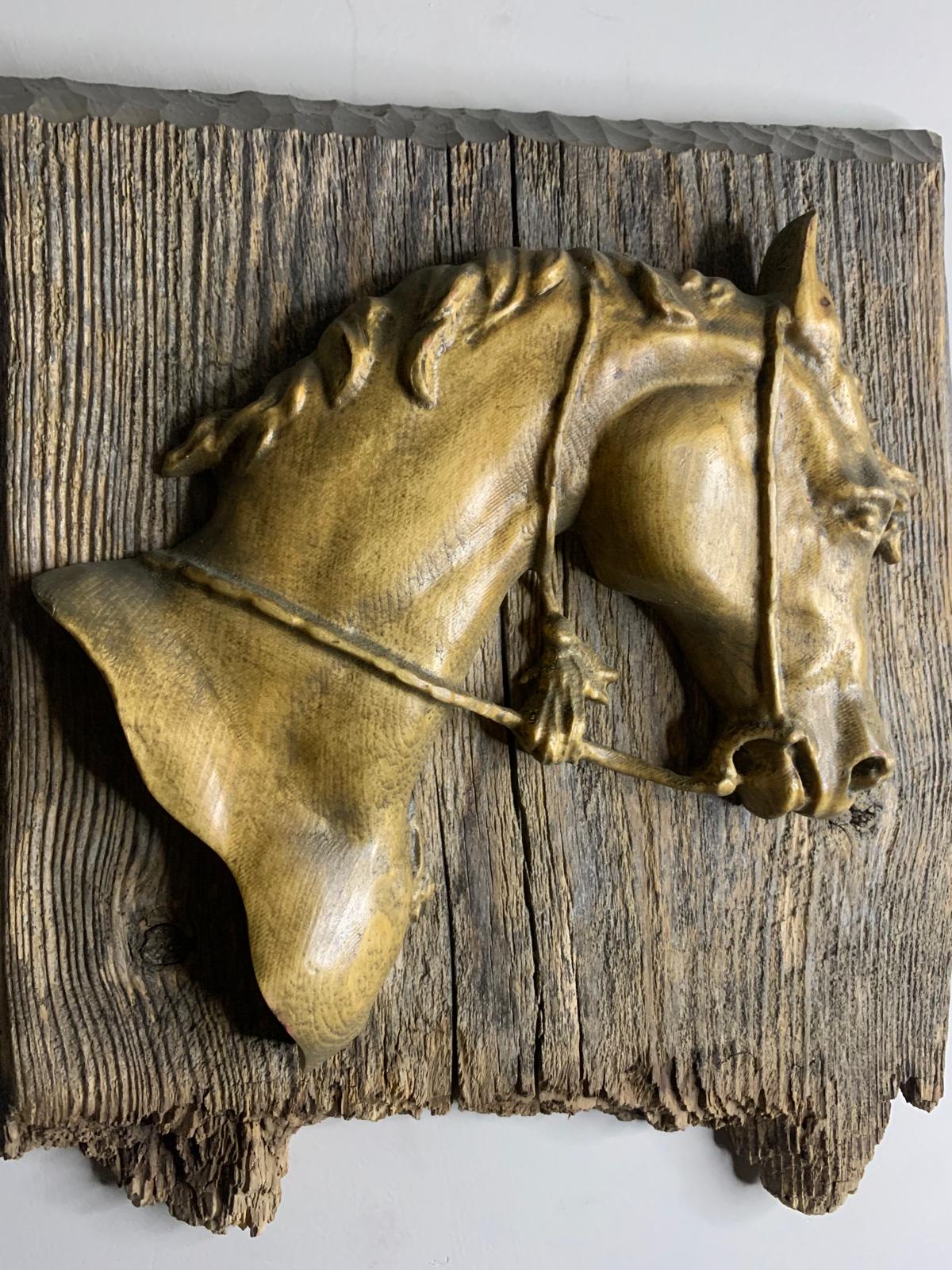Carved horse head sculpture mounted on weathered barnwood