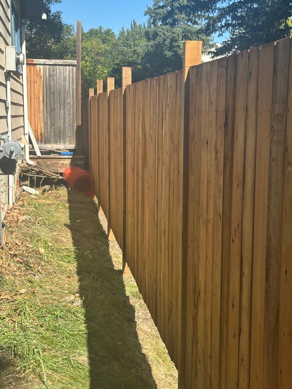 Finished cedar privacy fence with uniform pickets running along the side of a Calgary home