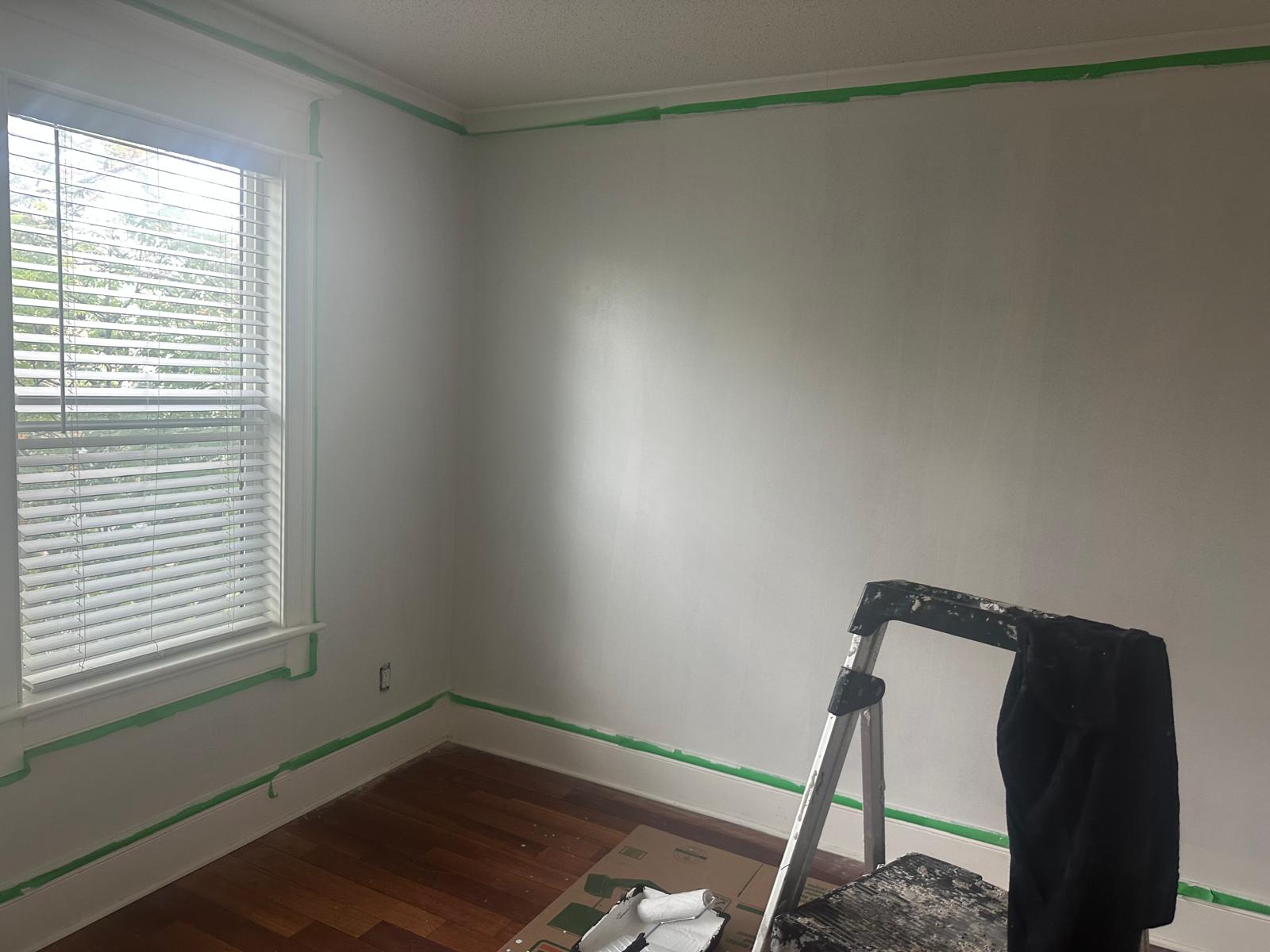 Interior room masked off with painter's tape, walls primed and ready for finish coat