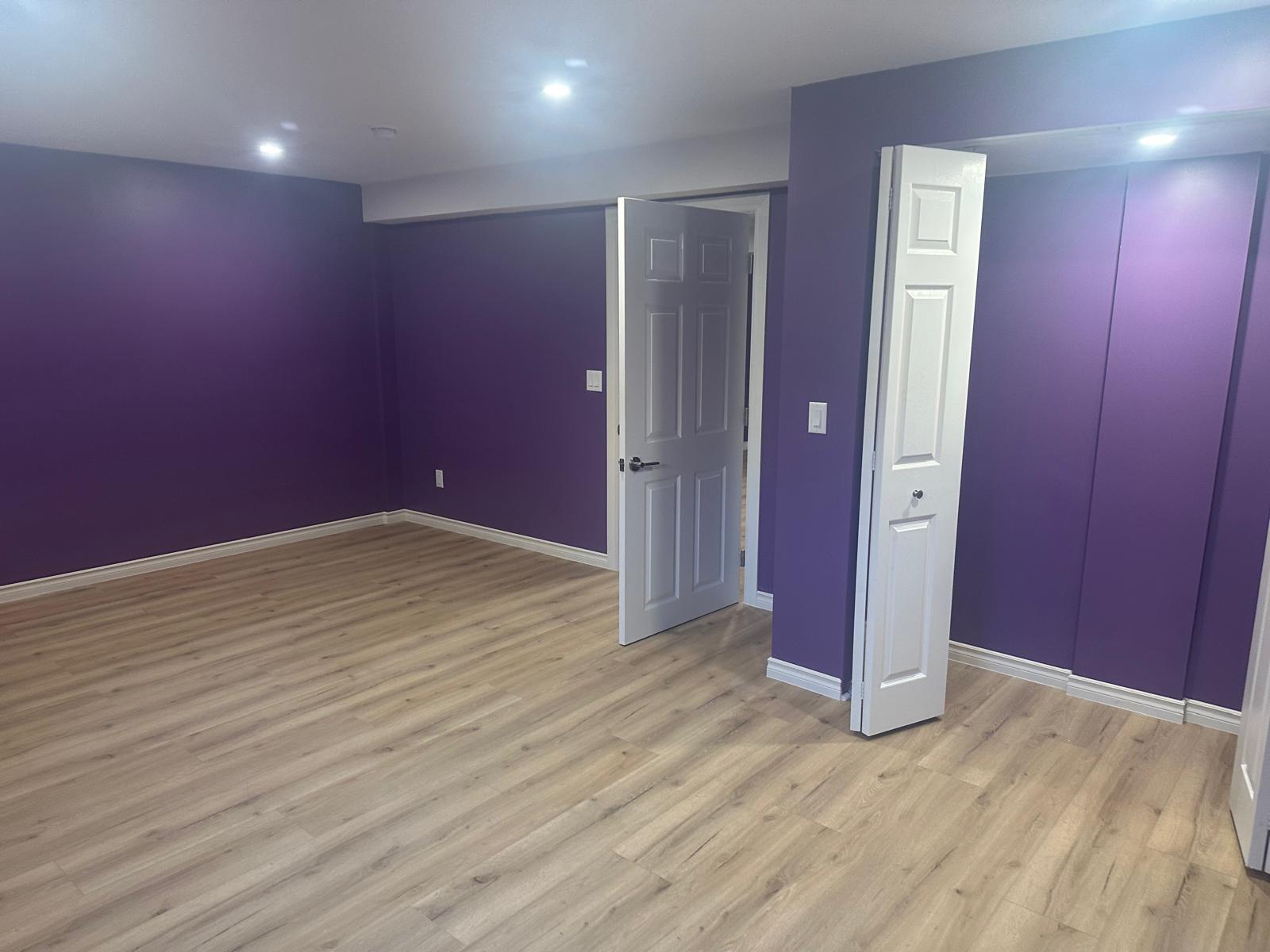Freshly painted basement bedroom with deep purple feature walls and crisp white trim
